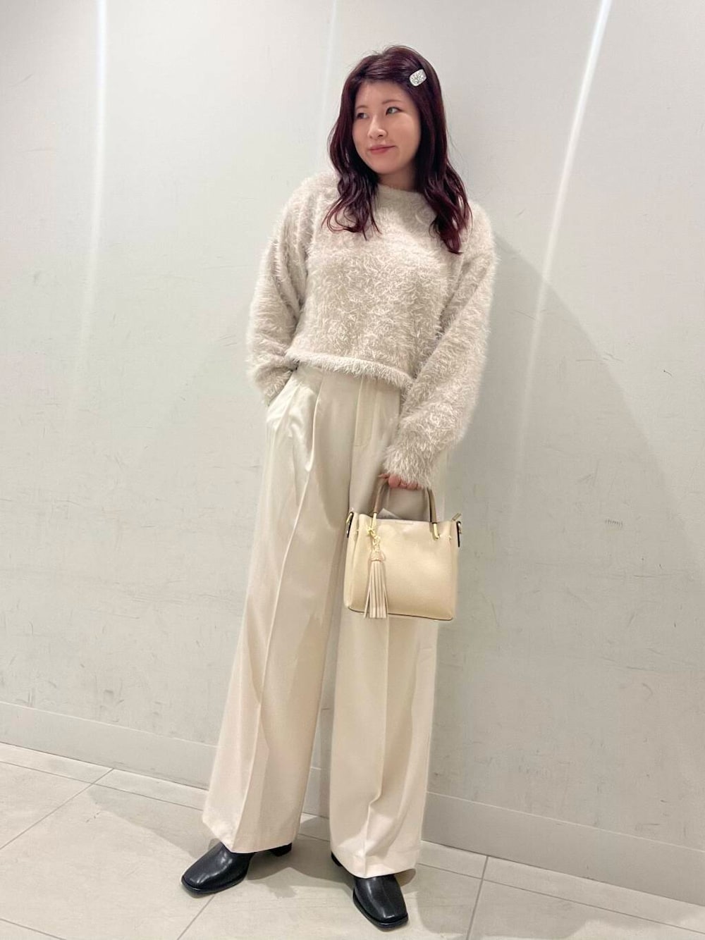 ホワイト系のトートバッグ、ブラック系のブーツ、ベージュ系のニット/セーターを着用したレディースの冬コーディネートの1枚目の写真