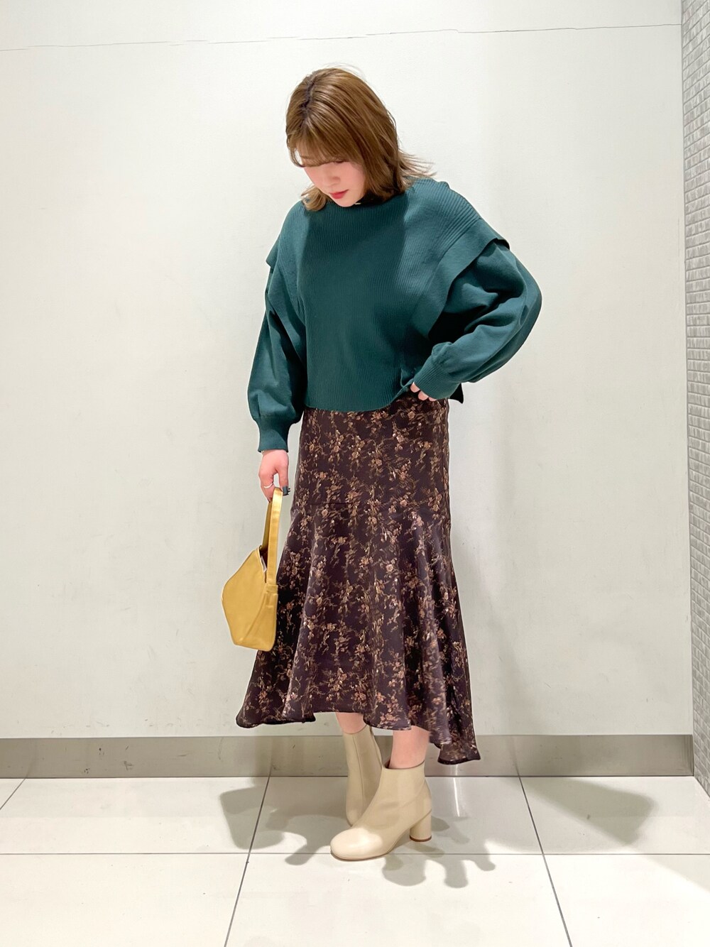 グリーン系のニット/セーター、ブラウン系のスカート、ホワイト系のブーツを着用したレディースの冬コーディネートの1枚目の写真