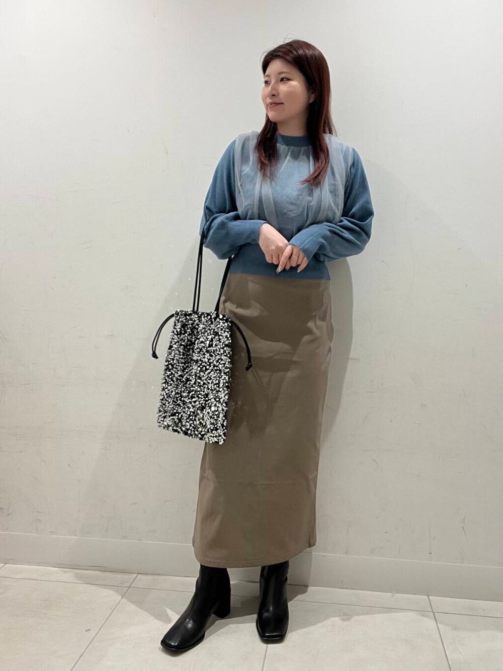 ブラウン系のスカート、ブラック系のブーツ、シルバー系のトートバッグを着用したレディースの冬コーディネートの1枚目の写真