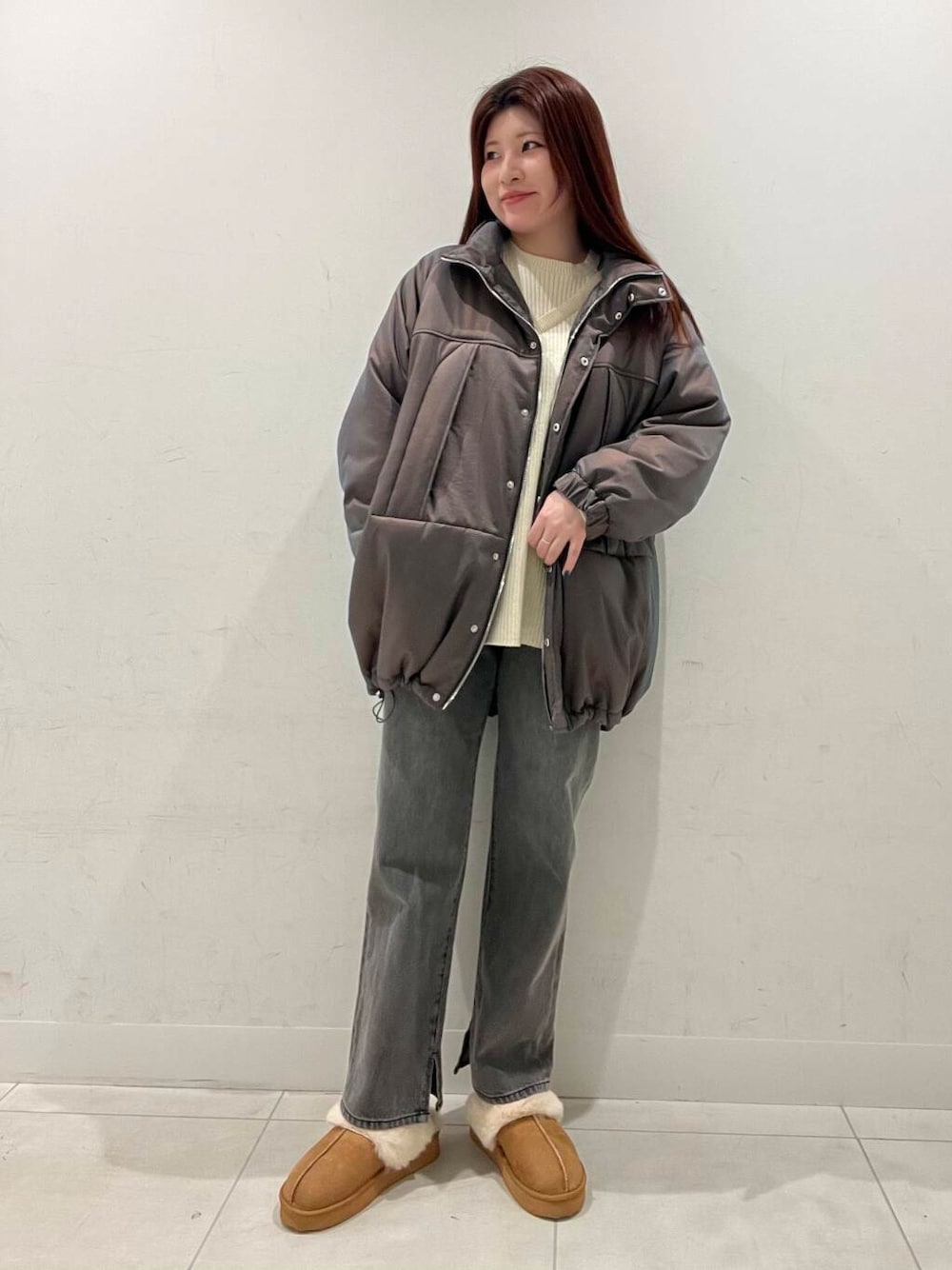 オレンジ系のハンドバッグ、ホワイト系のニット/セーター、ブラウン系のダウンジャケット/コートを着用したレディースの冬コーディネートの1枚目の写真