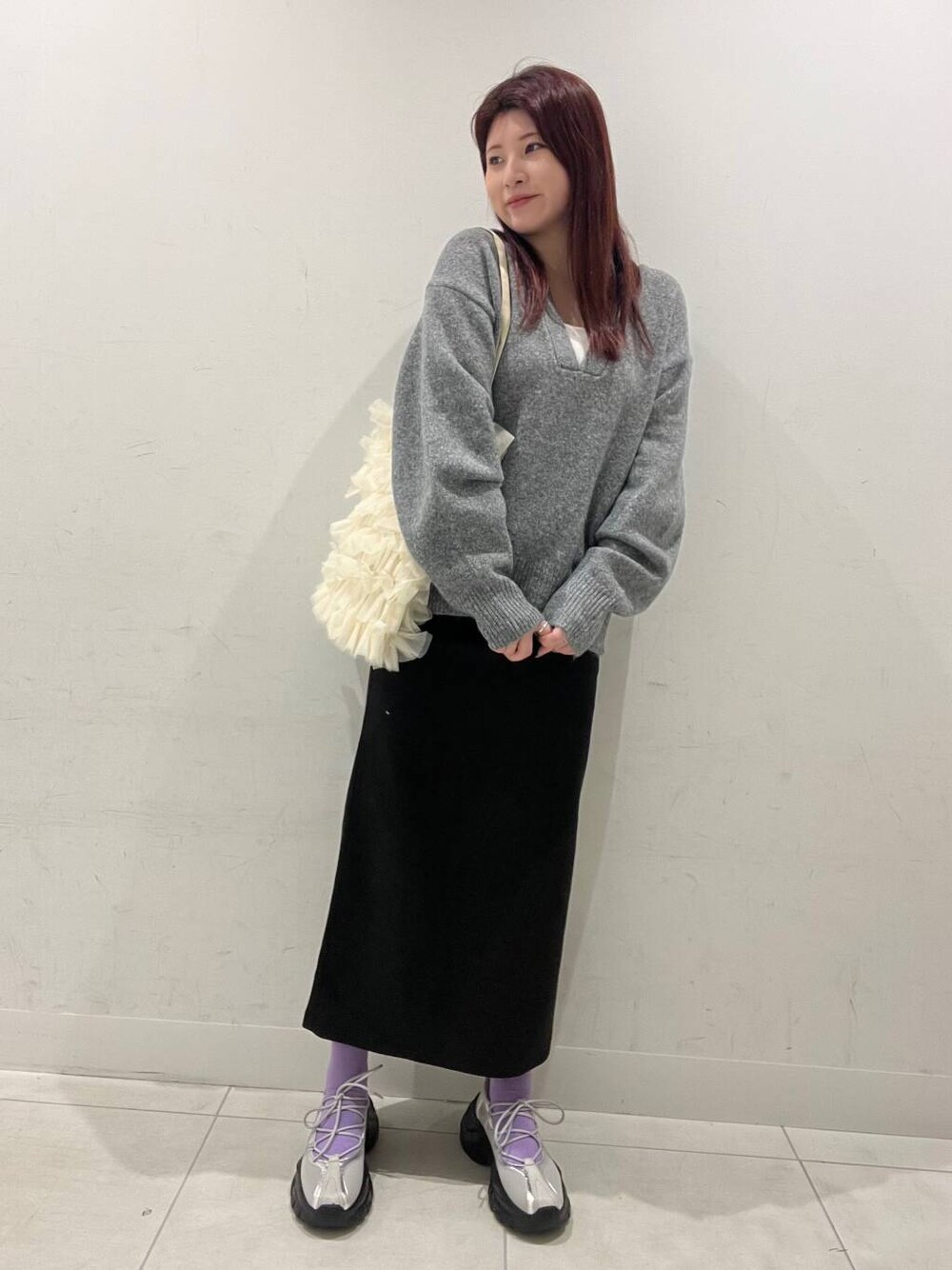 ホワイト系のトートバッグ、グレー系のスニーカー、グレー系のスカートを着用したレディースの冬コーディネートの1枚目の写真