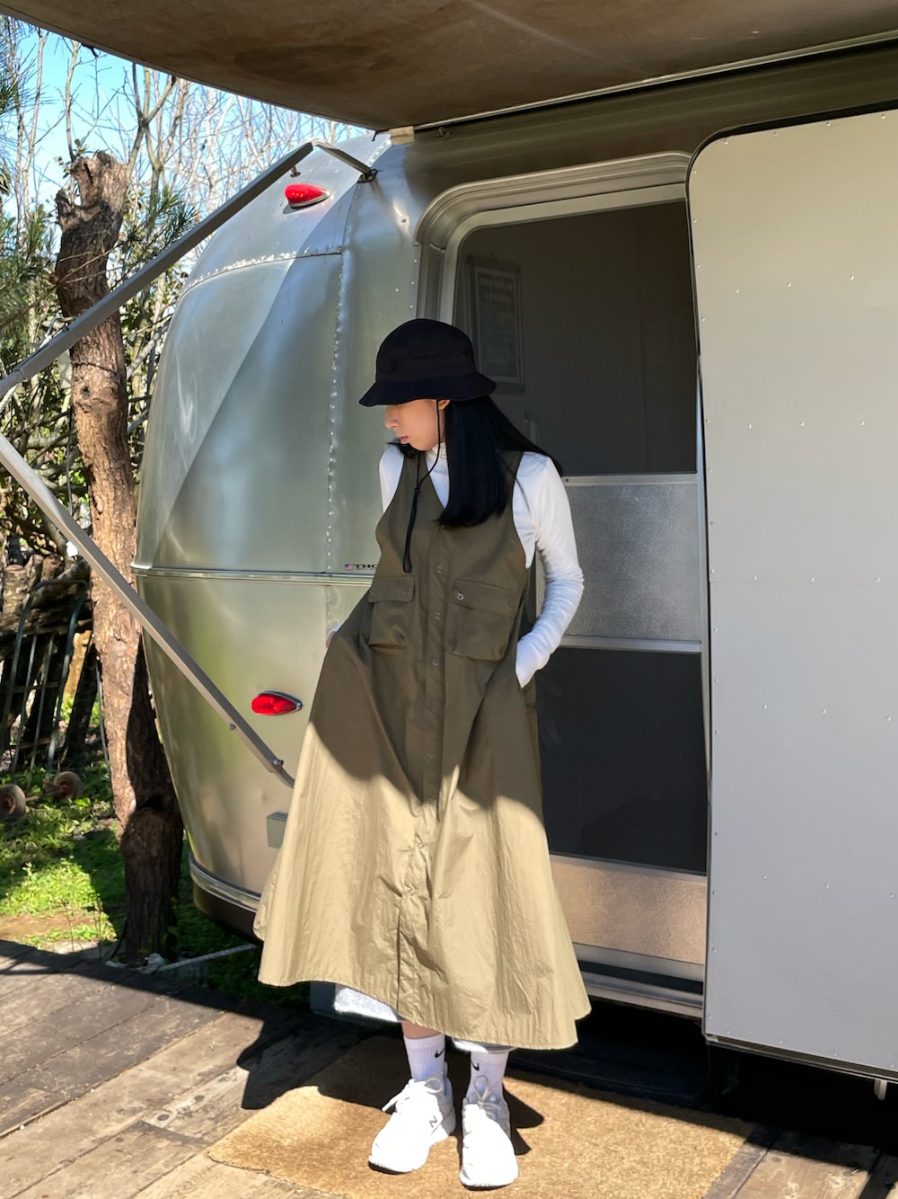 ベージュ系のスニーカー、その他のジャンパースカート、ブラック系の帽子を着用したレディースの春コーディネートの1枚目の写真