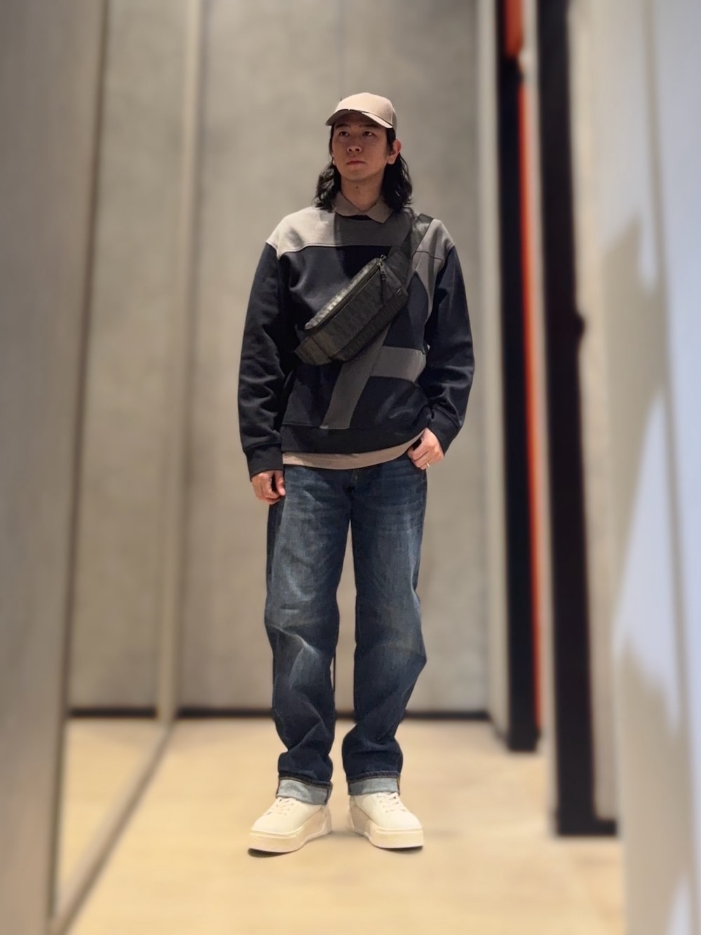 ホワイト系のスニーカー、ブルー系のデニムパンツ、ベージュ系のポロシャツを着用したメンズの冬コーディネートの1枚目の写真