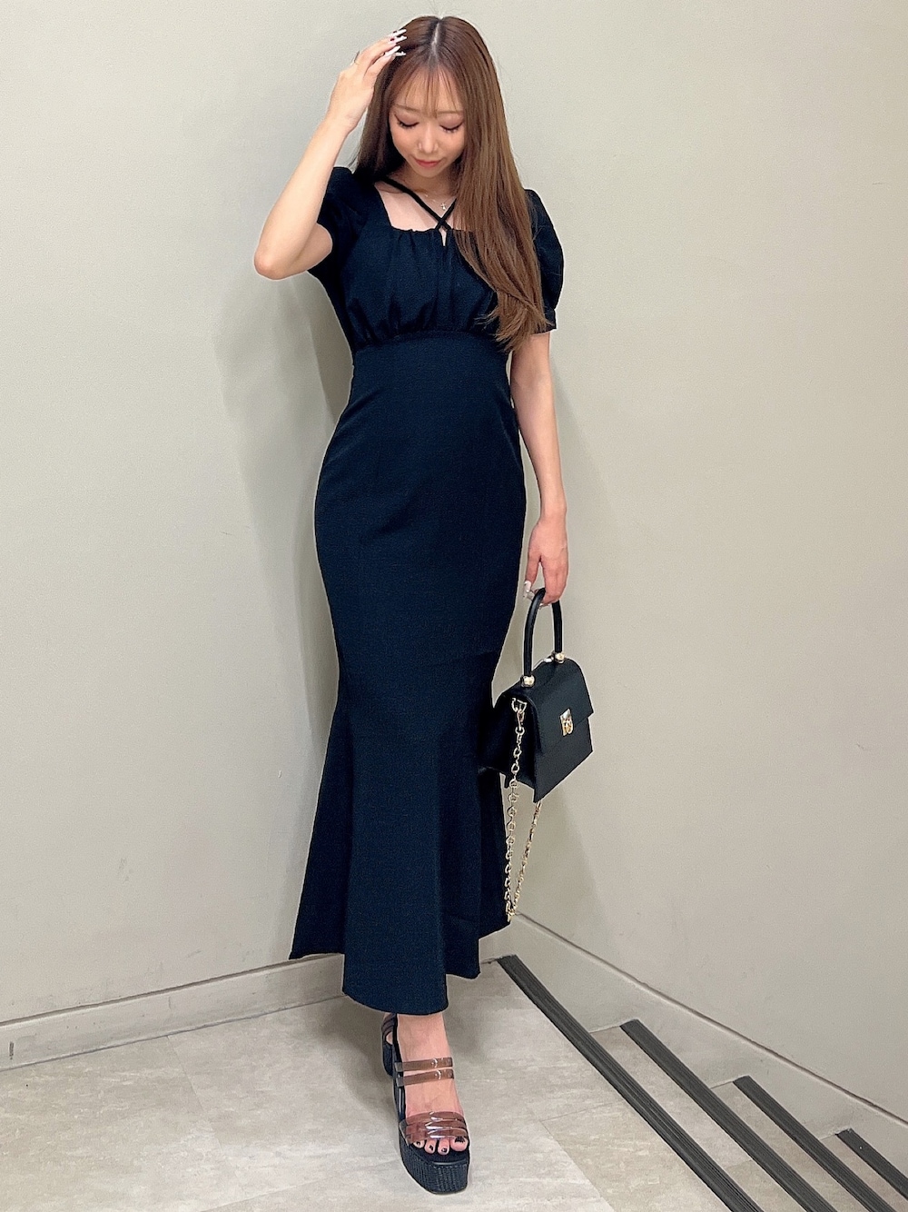 ブラック系のワンピース、ブラック系のサンダル、ブラック系のハンドバッグを着用したレディースの春コーディネートの1枚目の写真