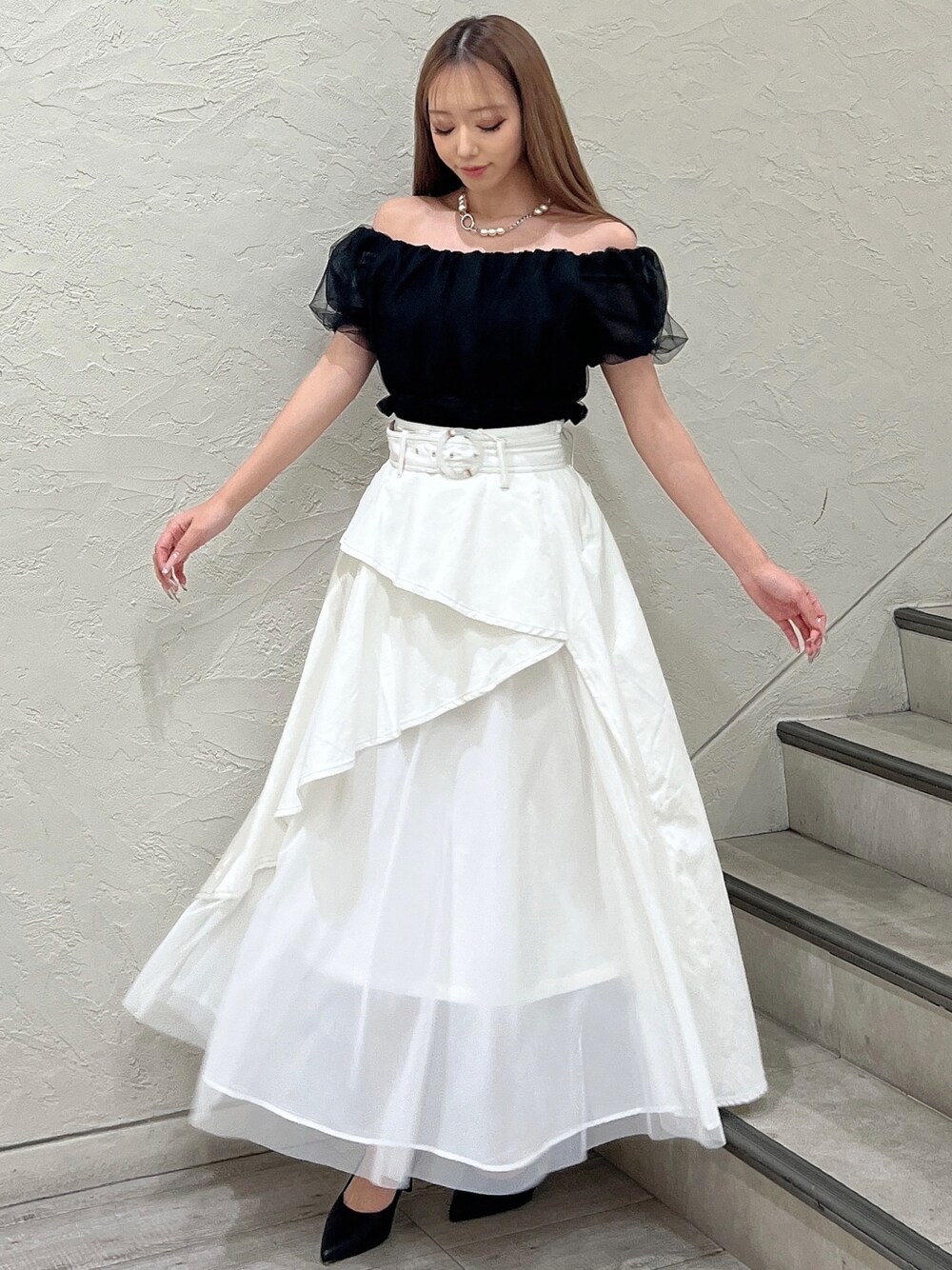 ブラック系のシャツ/ブラウス、ホワイト系のデニムスカート、ブラック系のパンプスを着用したレディースの春コーディネートの1枚目の写真