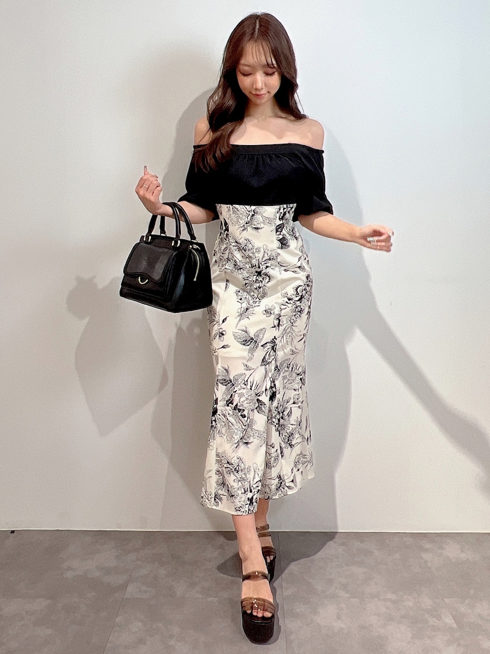 ブラック系のワンピース、ブラック系のサンダル、ブラック系のハンドバッグを着用したレディースの冬コーディネートの1枚目の写真