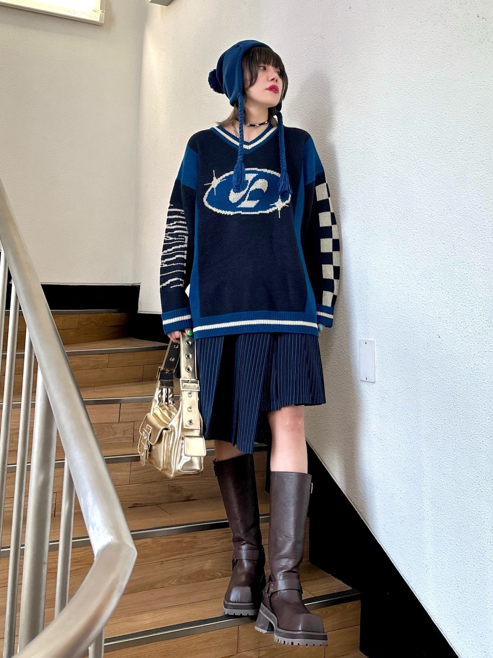 ブルー系のスカート、ゴールド系のハンドバッグ、ブラック系のニット/セーターを着用したレディースの夏コーディネートの1枚目の写真