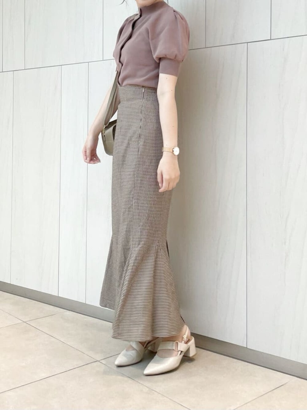 ブラウン系のスカート、ピンク系のニット/セーター、ベージュ系のハンドバッグを着用したレディースの秋コーディネートの1枚目の写真