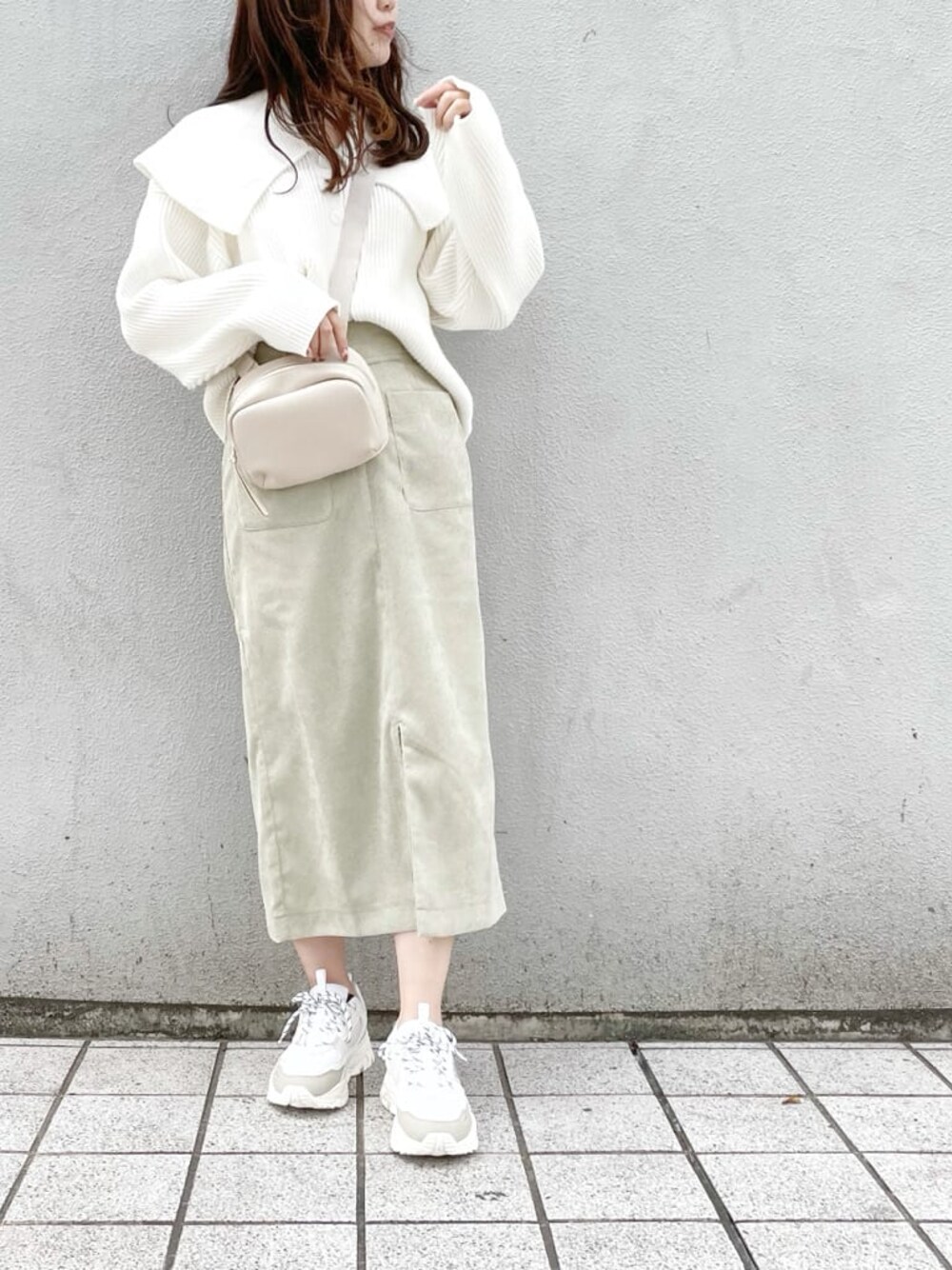 ホワイト系のスニーカー、グリーン系のスカート、ホワイト系のハンドバッグを着用したレディースの秋コーディネートの1枚目の写真