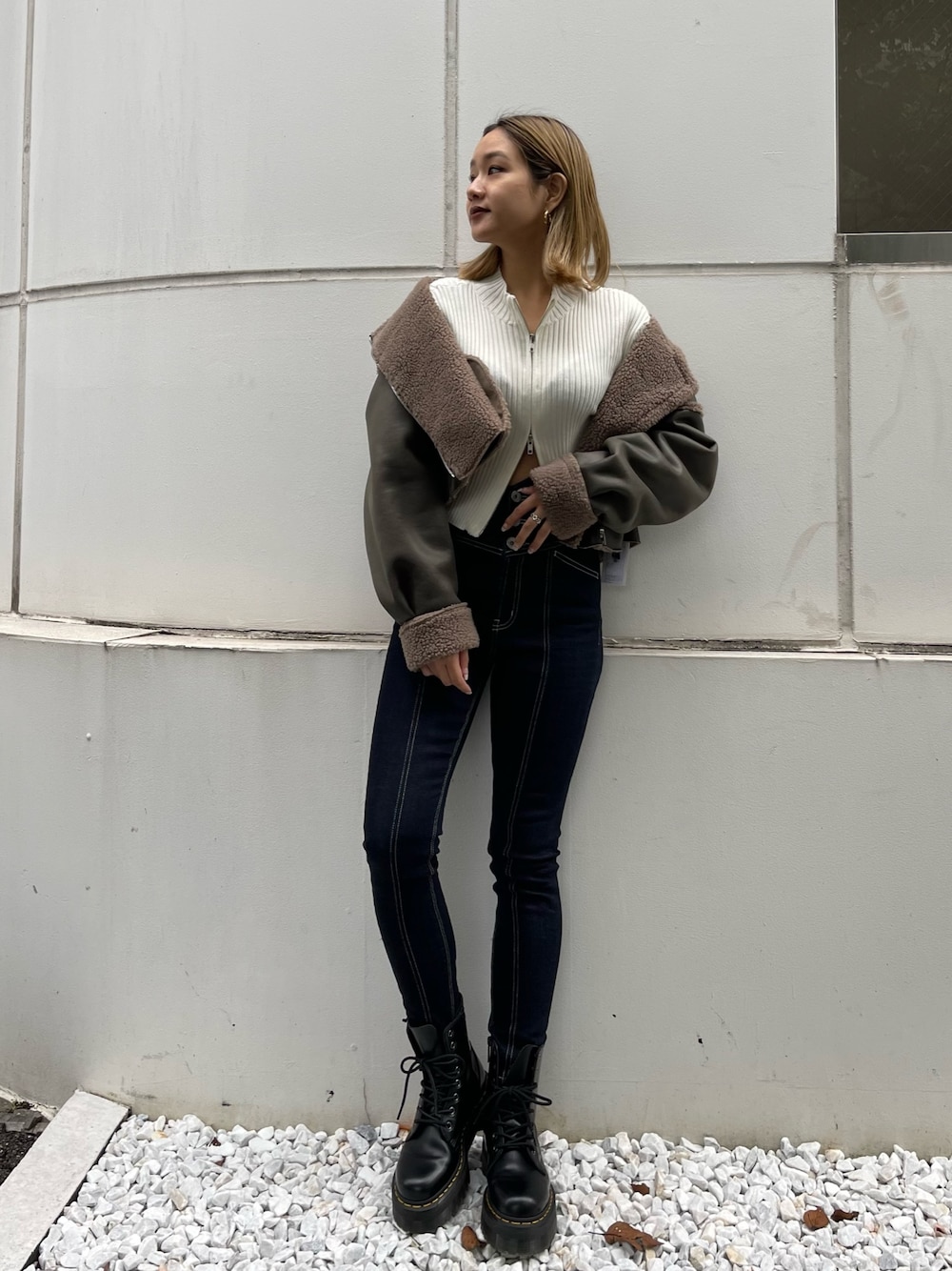 ブラック系のブーツ、ホワイト系のニット/セーター、グリーン系のブルゾンを着用したレディースの秋コーディネートの1枚目の写真