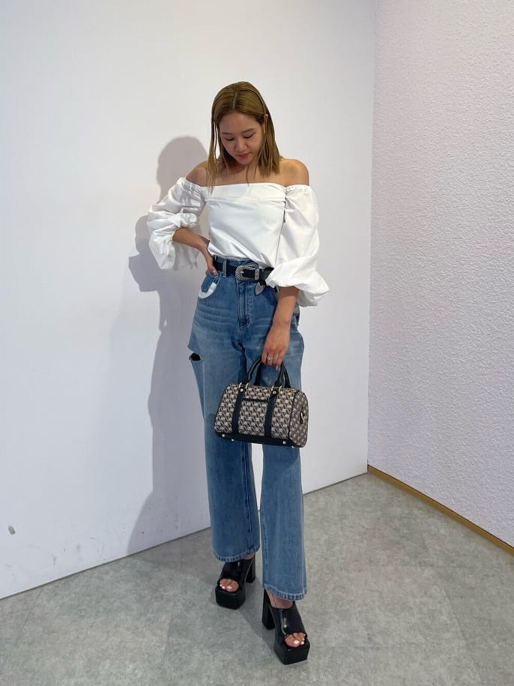 ブラック系のサンダル、ブラック系のボストンバッグ、ブルー系のデニムパンツを着用したレディースの夏コーディネートの1枚目の写真