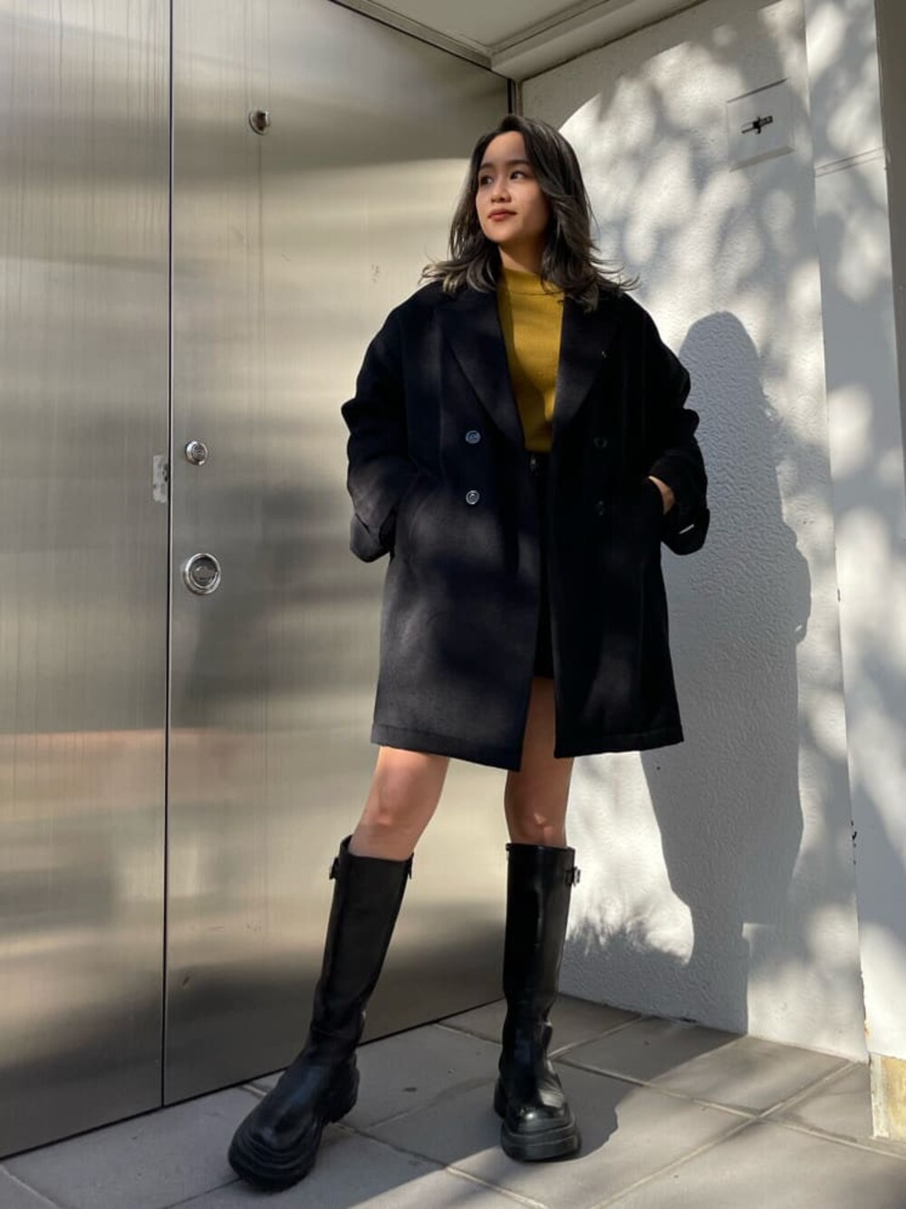 ブラック系のその他アウター、ブラック系のスカート、ブラック系のブーツを着用したレディースの秋コーディネートの1枚目の写真