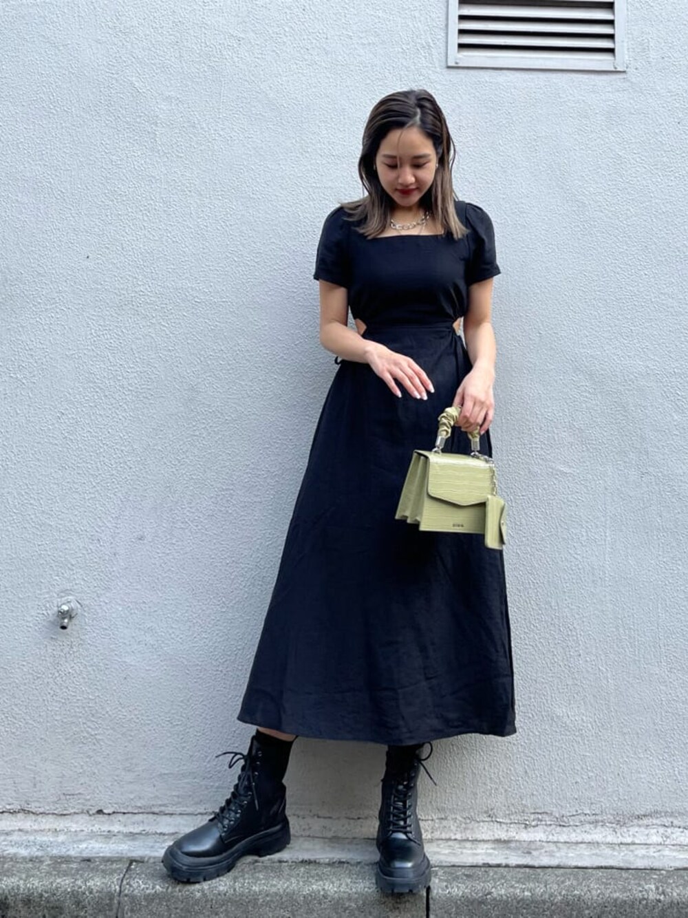 ブラック系のブーツ、グリーン系のショルダーバッグ、ブラック系のワンピースを着用したレディースの春コーディネートの1枚目の写真