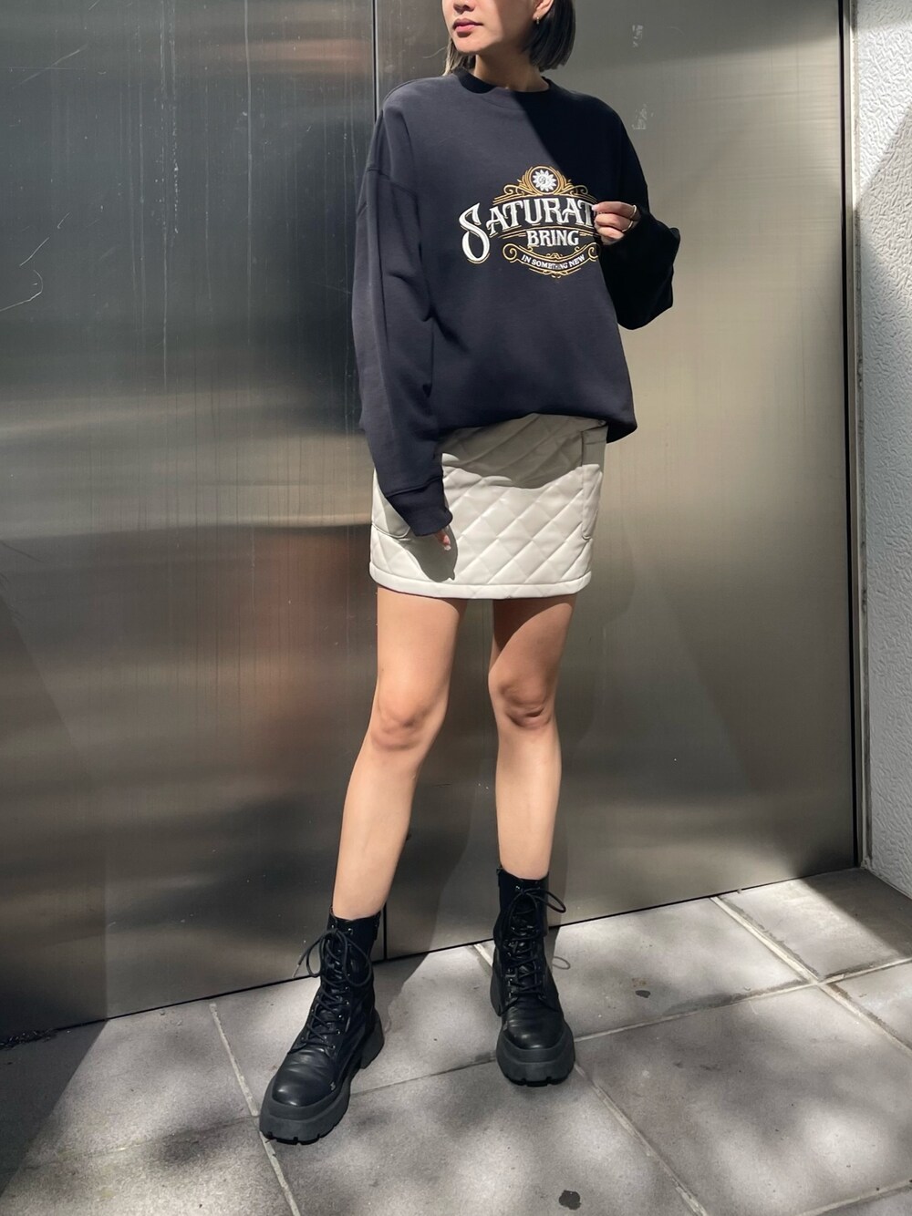 ブラック系のスウェット、ホワイト系のスカート、ブラック系のブーツを着用したレディースの秋コーディネートの1枚目の写真