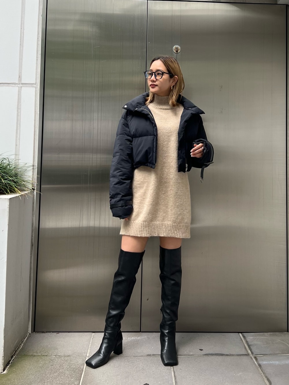 ベージュ系のワンピース、ブラック系のダウンジャケット/コート、ブラック系のブーツを着用したレディースの秋コーディネートの1枚目の写真