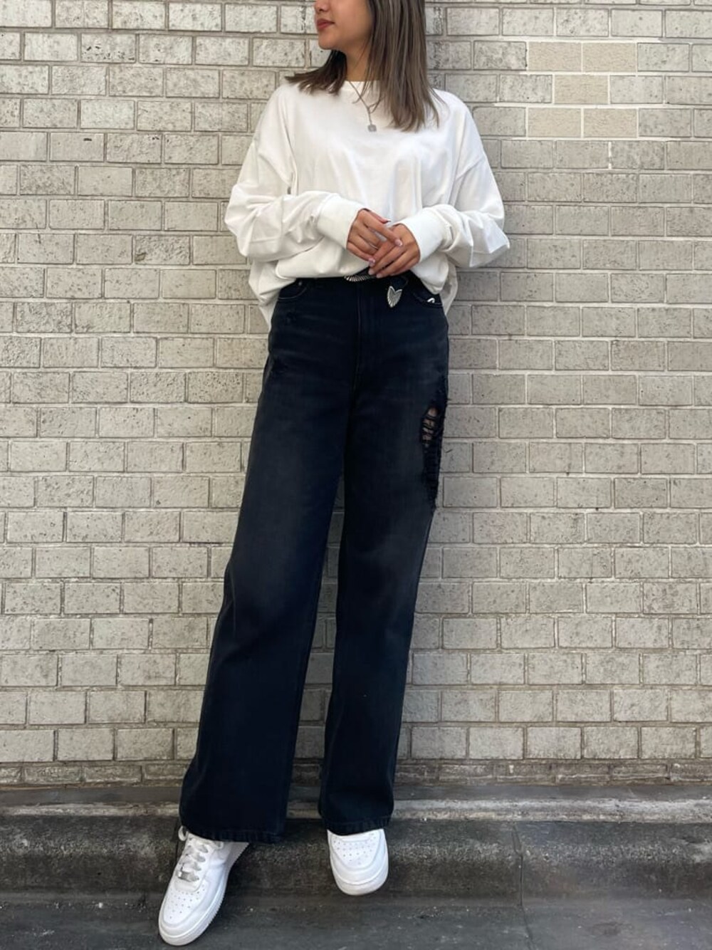 ブラック系のデニムパンツ、ホワイト系のTシャツ/カットソー、ホワイト系のベルトを着用したレディースの冬コーディネートの1枚目の写真