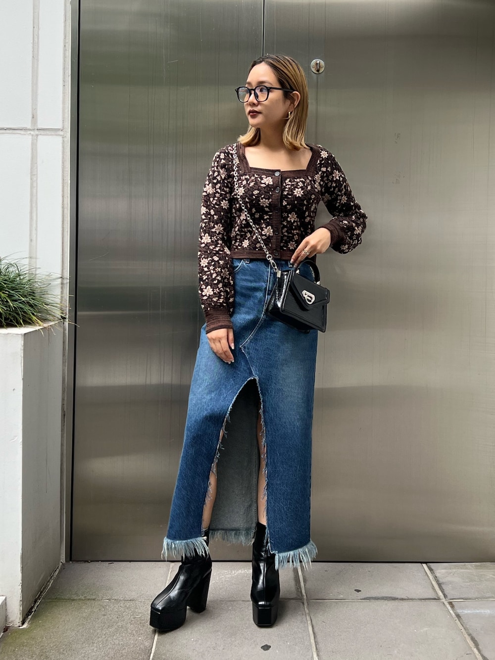 ブルー系のデニムスカート、ブラック系のブーツ、ブラック系のニット/セーターを着用したレディースの秋コーディネートの1枚目の写真