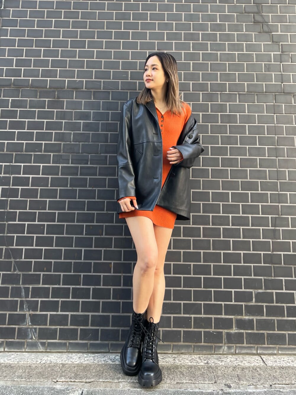 オレンジ系のワンピース、ブラック系のテーラードジャケット、ブラック系のブーツを着用したレディースの冬コーディネートの1枚目の写真