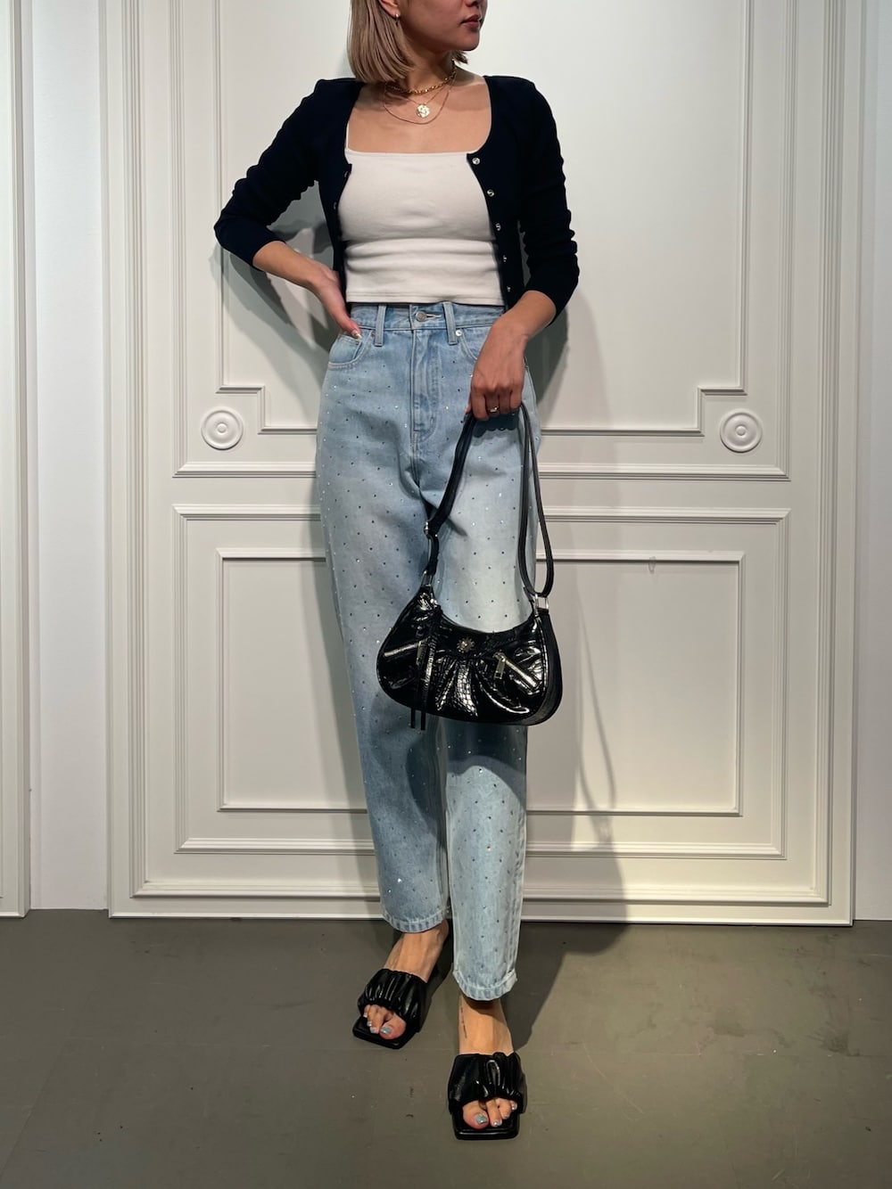 ブラック系のショルダーバッグ、ブルー系のデニムパンツ、ブラック系のサンダルを着用したレディースの夏コーディネートの1枚目の写真