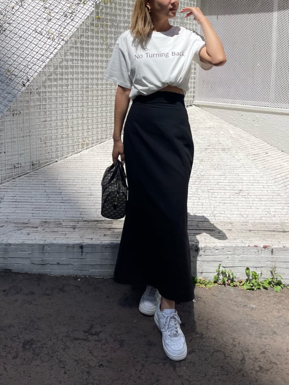 ブラック系のスカート、ブラック系のボストンバッグ、ホワイト系のTシャツ/カットソーを着用したレディースの夏コーディネートの1枚目の写真