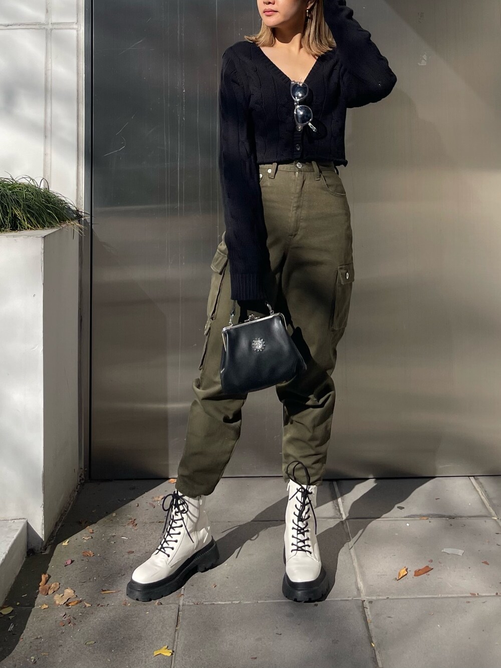 ブラック系のショルダーバッグ、ブラック系のカーディガン/ボレロ、ホワイト系のブーツを着用したレディースの冬コーディネートの1枚目の写真