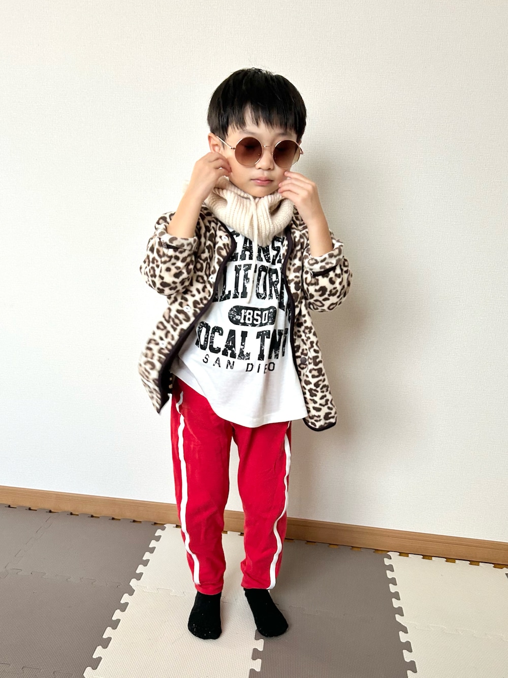 レッド系のスウェットパンツ、ベージュ系のカーディガン/ボレロ、ホワイト系のTシャツ/カットソーを着用したキッズの秋コーディネートの1枚目の写真