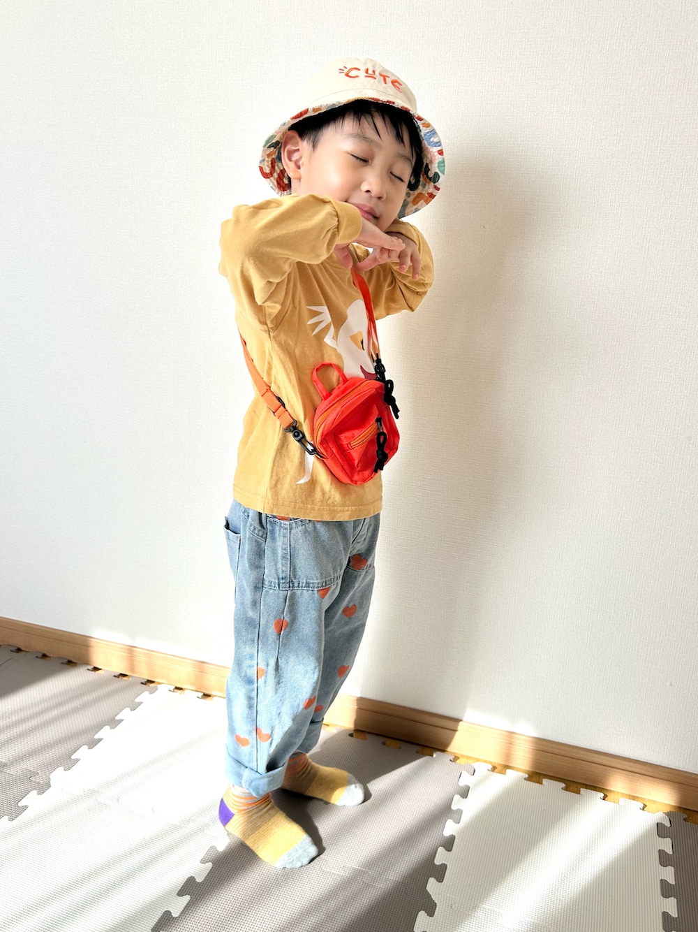 イエロー系のTシャツ/カットソー、ブルー系のデニムパンツ、オレンジ系のショルダーバッグを着用したキッズの春コーディネートの1枚目の写真