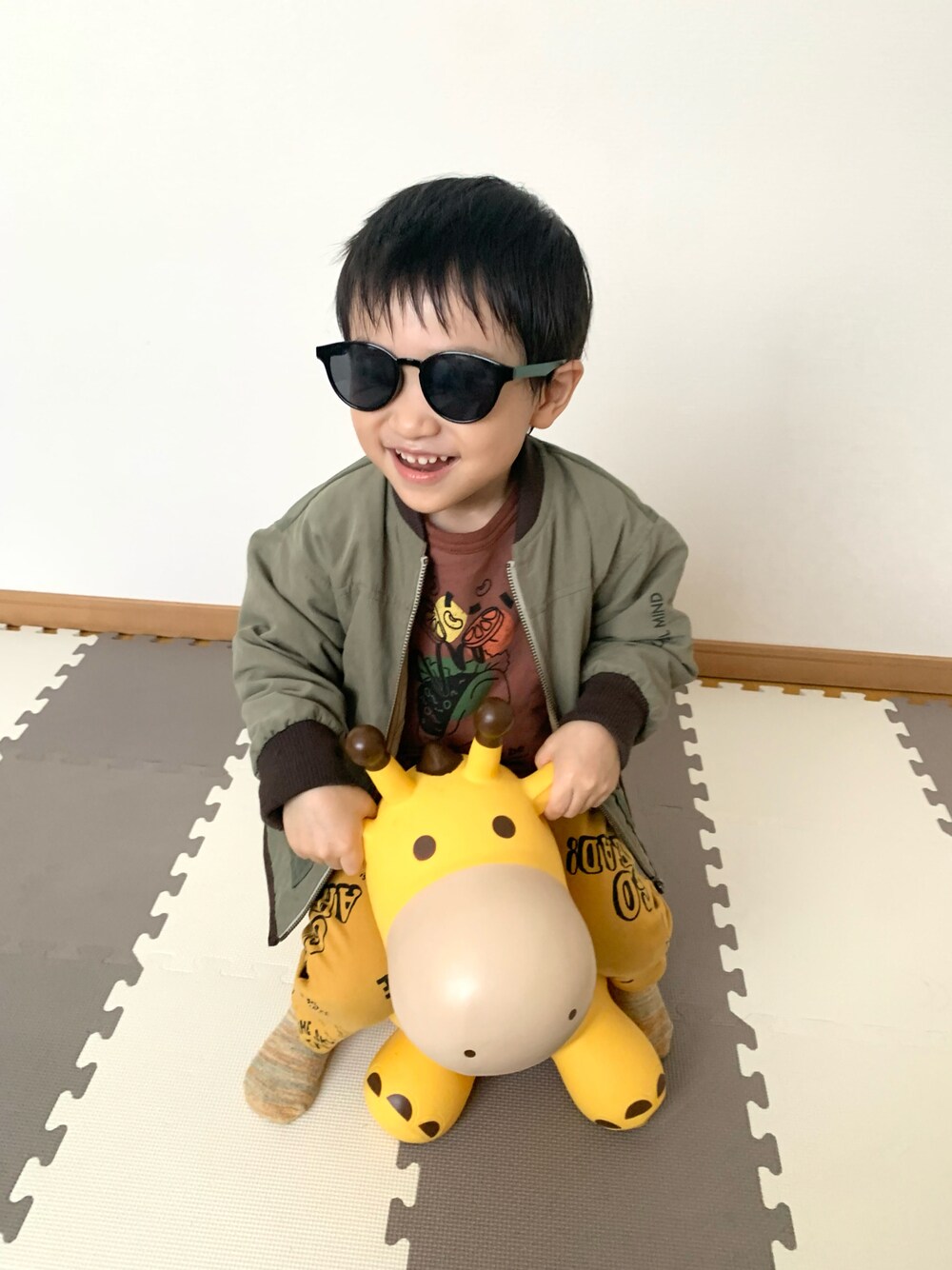 イエロー系のチノパンツ、グリーン系のジャケット/アウター、ブラウン系のスウェットを着用したキッズの冬コーディネートの1枚目の写真