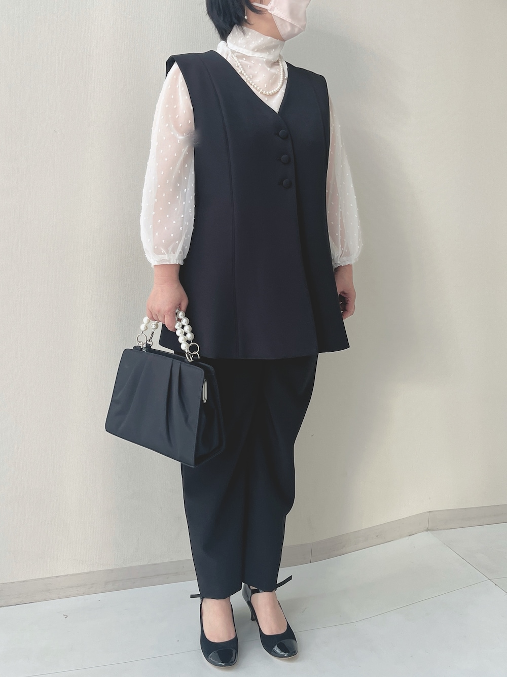 ブラック系のスーツセット、ブラック系のバッグ、ホワイト系のピアス(両耳用)を着用したレディースの冬コーディネートの1枚目の写真