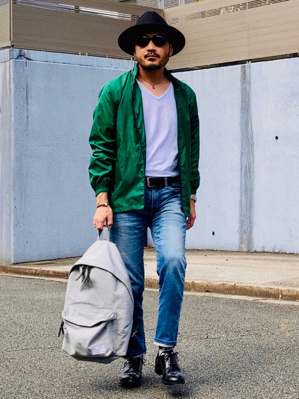 グリーン系のナイロンジャケット、ブルー系のデニムパンツ、ブラック系のドレスシューズを着用したメンズの秋コーディネートの1枚目の写真