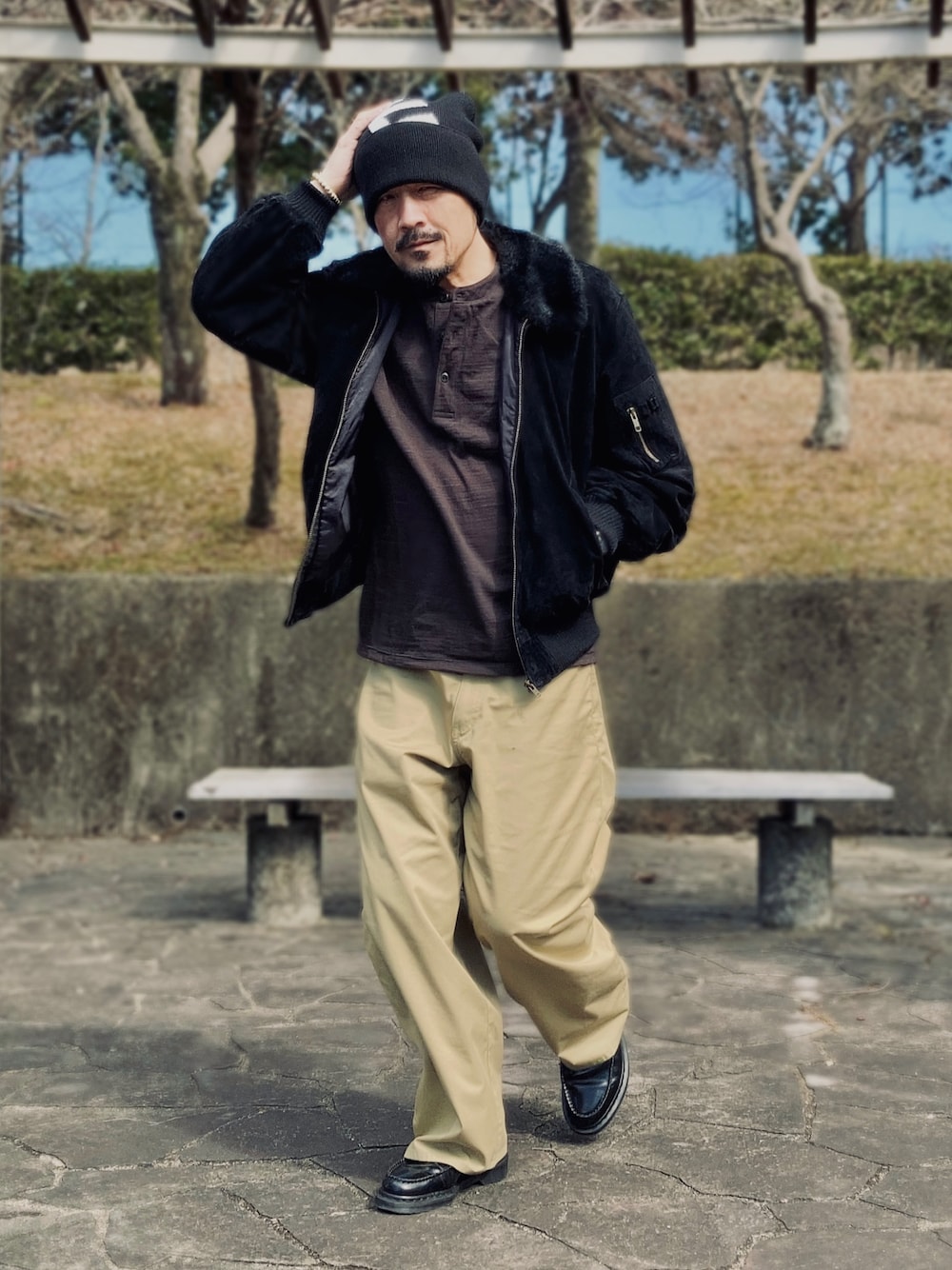 ブラック系のブルゾン、ブラウン系のTシャツ/カットソー、ベージュ系のチノパンツを着用したメンズの冬コーディネートの1枚目の写真