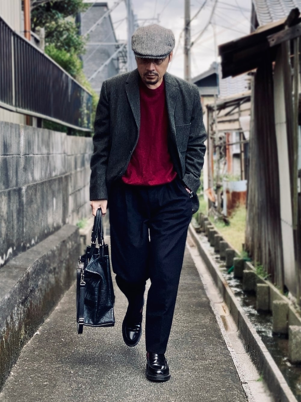 レッド系のニット/セーター、グレー系のテーラードジャケット、ブラック系のスラックスを着用したメンズの秋コーディネートの1枚目の写真