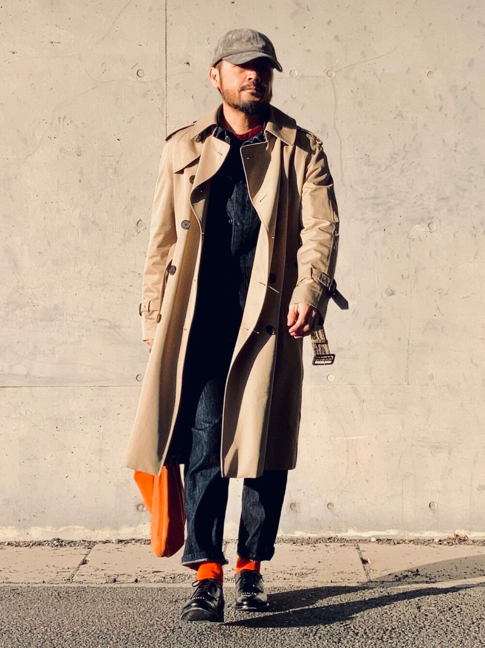 レッド系のニット/セーター、ブルー系のデニムジャケット、ベージュ系のトレンチコートを着用したメンズの冬コーディネートの1枚目の写真