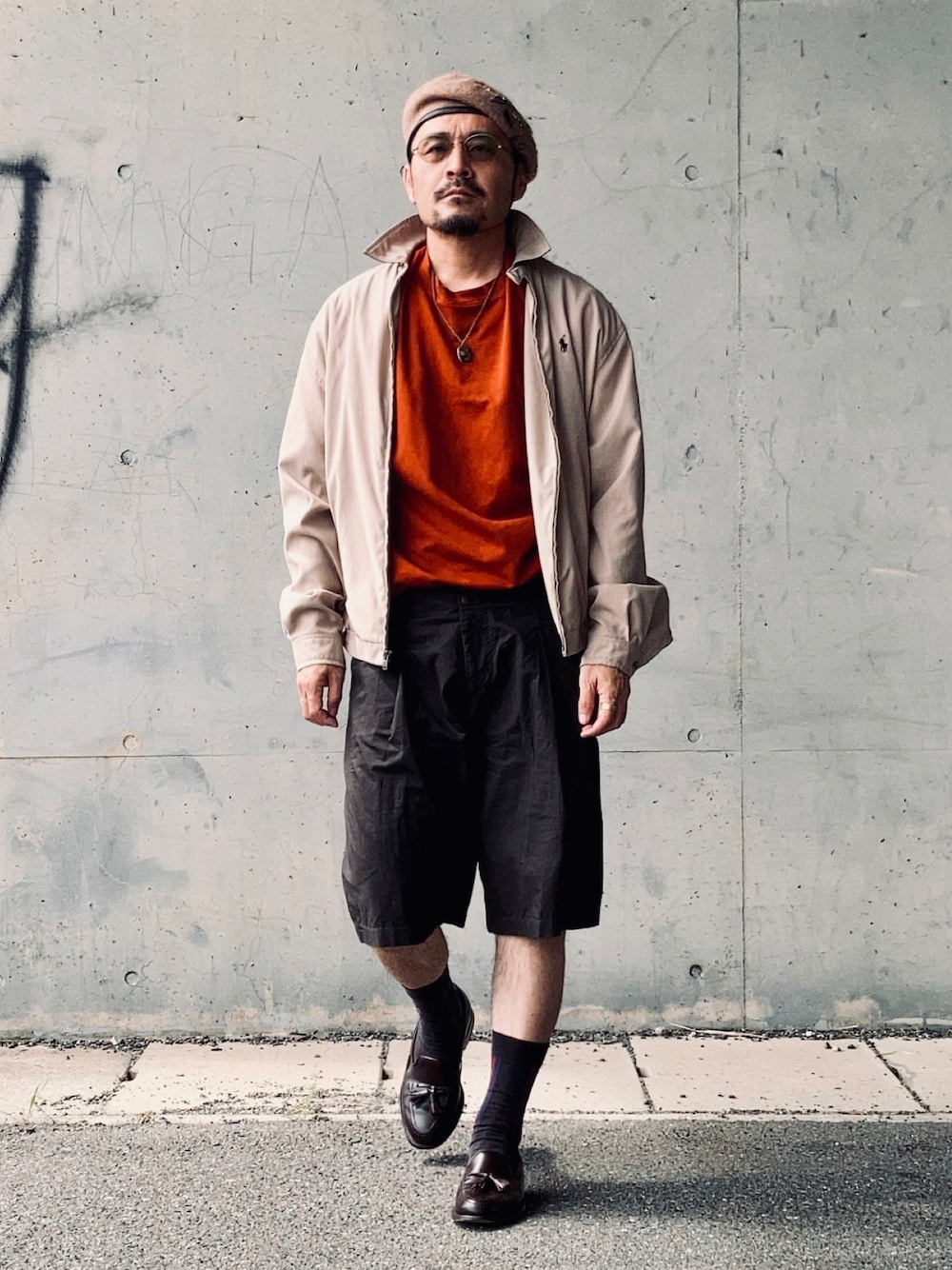 オレンジ系のTシャツ/カットソー、ベージュ系のブルゾン、ブラウン系のパンツを着用したメンズの秋コーディネートの1枚目の写真