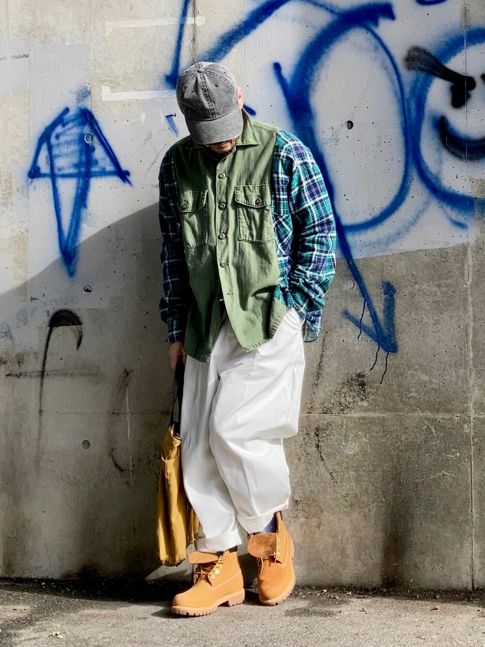 グリーン系のシャツ/ブラウス、ホワイト系のスラックス、イエロー系のブーツを着用したメンズの春コーディネートの1枚目の写真