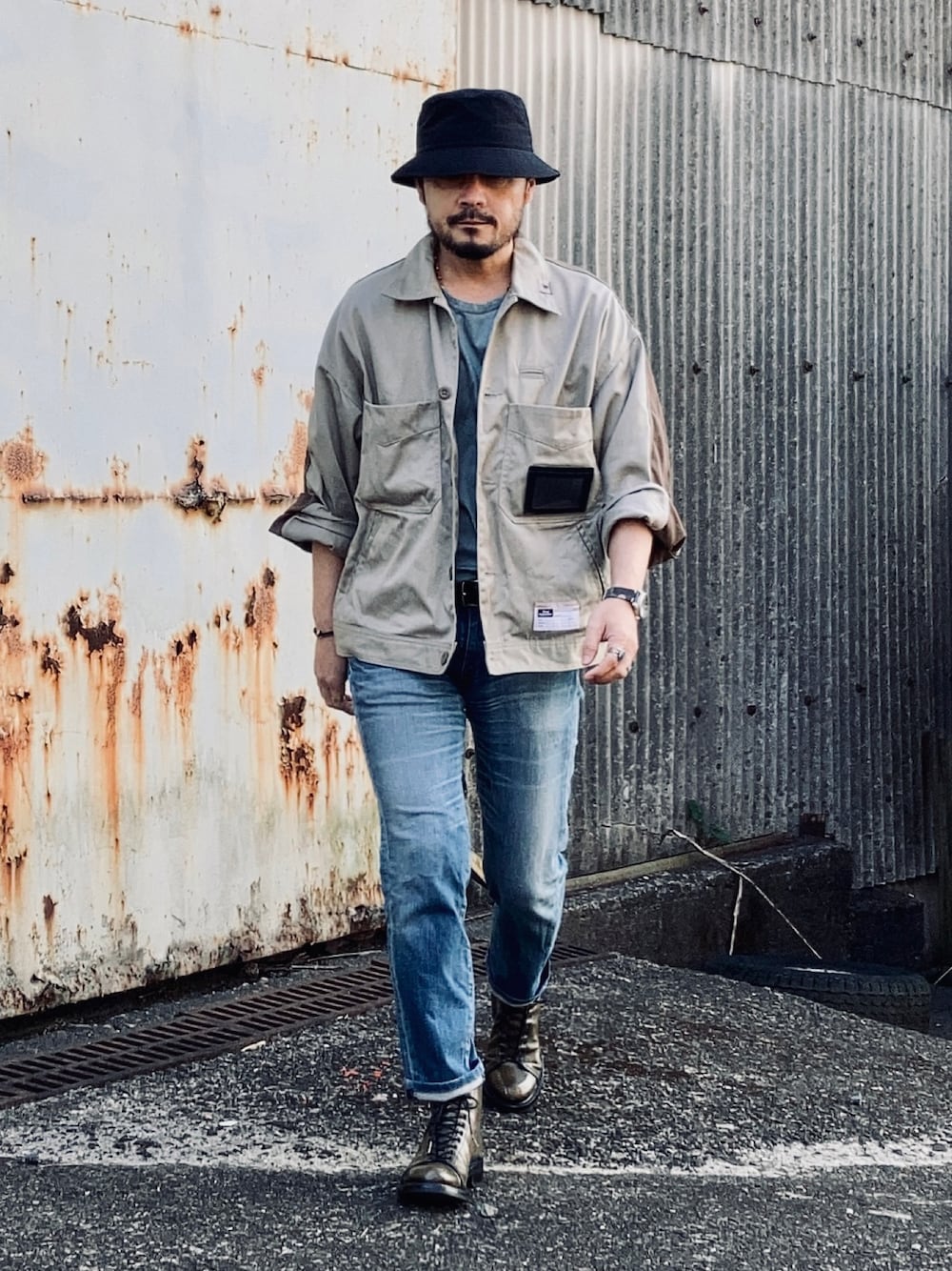 グリーン系のTシャツ/カットソー、ベージュ系のその他アウター、ブルー系のデニムパンツを着用したメンズの春コーディネートの1枚目の写真