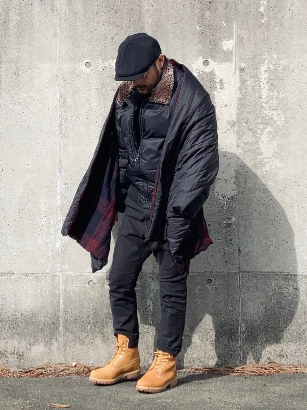 ブラック系のダウンジャケット/コート、ブラック系のデニムパンツ、イエロー系のブーツを着用したメンズの冬コーディネートの1枚目の写真