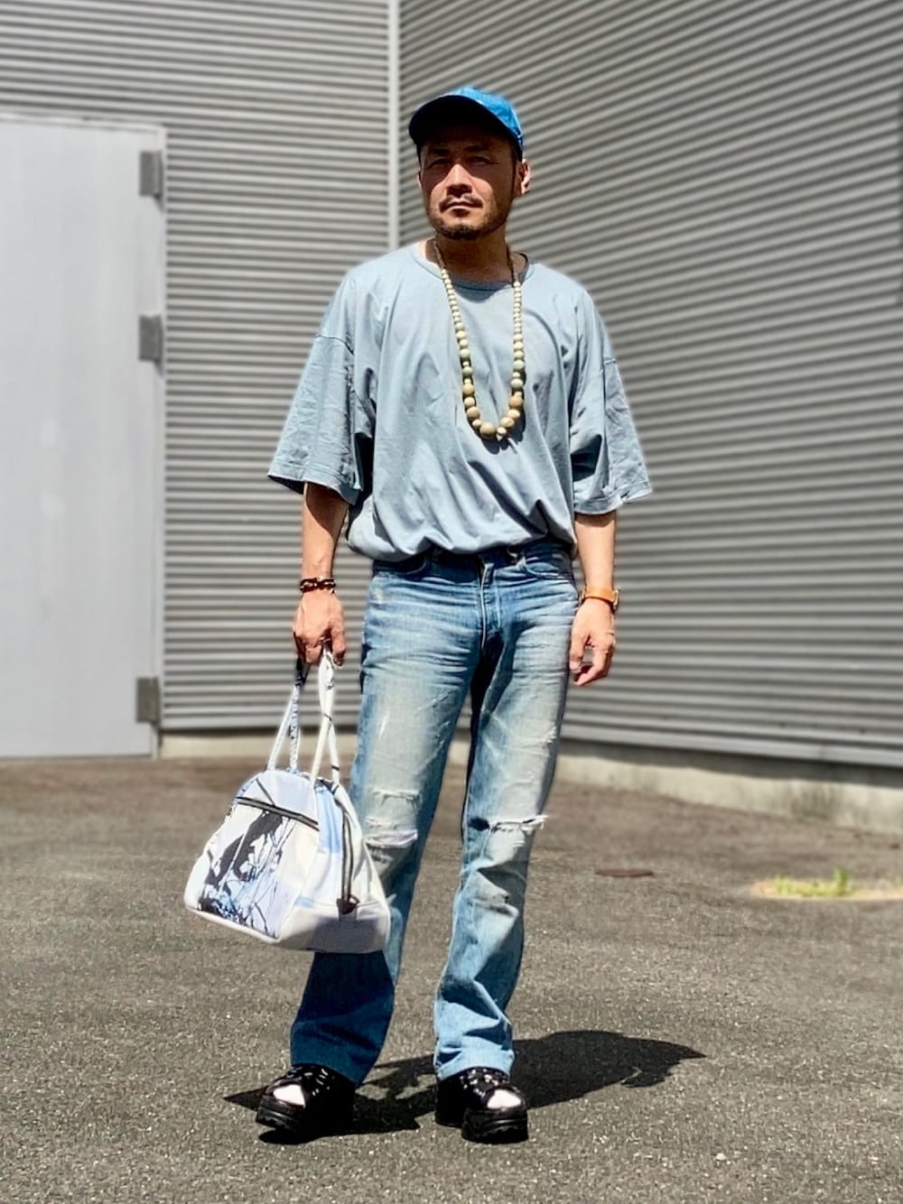 グリーン系のTシャツ/カットソー、ブルー系のデニムパンツ、ブラック系のサンダルを着用したメンズの夏コーディネートの1枚目の写真