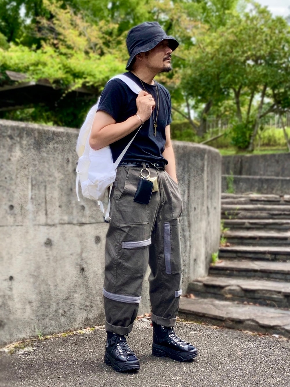 ブラック系のTシャツ/カットソー、グリーン系のその他パンツ、ブラック系のサンダルを着用したメンズの秋コーディネートの1枚目の写真