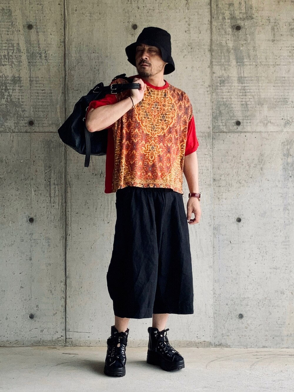 レッド系のTシャツ/カットソー、ブラック系のその他パンツ、ブラック系のサンダルを着用したメンズの夏コーディネートの1枚目の写真