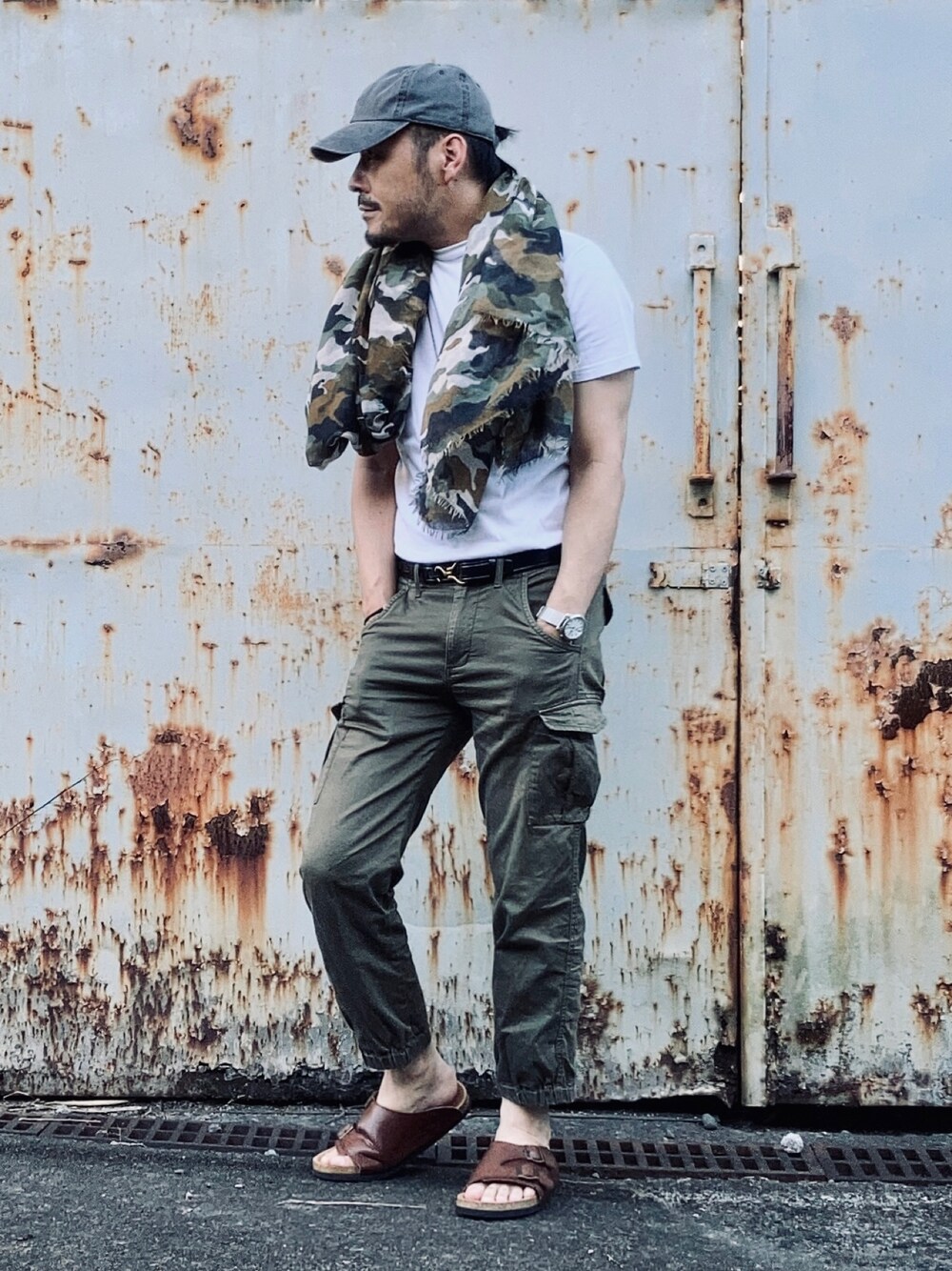 ホワイト系のTシャツ/カットソー、グリーン系のパンツ、ブラウン系のサンダルを着用したメンズの夏コーディネートの1枚目の写真