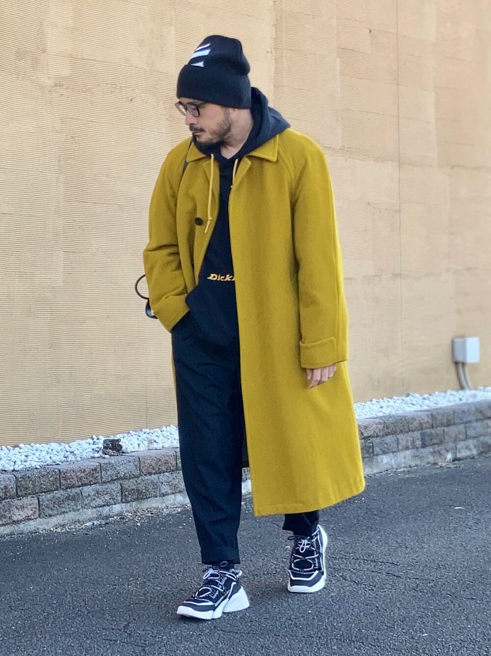 ブラック系のパーカー、イエロー系のステンカラーコート、ブラック系のその他パンツを着用したメンズの冬コーディネートの1枚目の写真