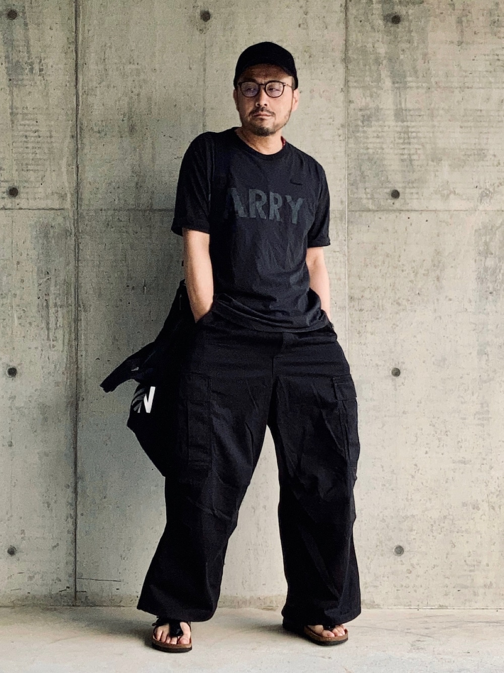 ブラック系のTシャツ/カットソー、ブラック系のカーゴパンツ、ブラック系のサンダルを着用したメンズの夏コーディネートの1枚目の写真