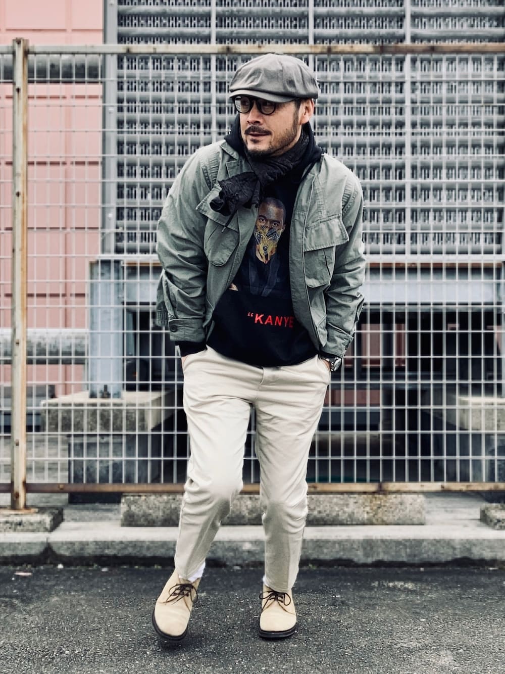 ブラック系のパーカー、グリーン系のミリタリージャケット、ベージュ系のチノパンツを着用したメンズの冬コーディネートの1枚目の写真