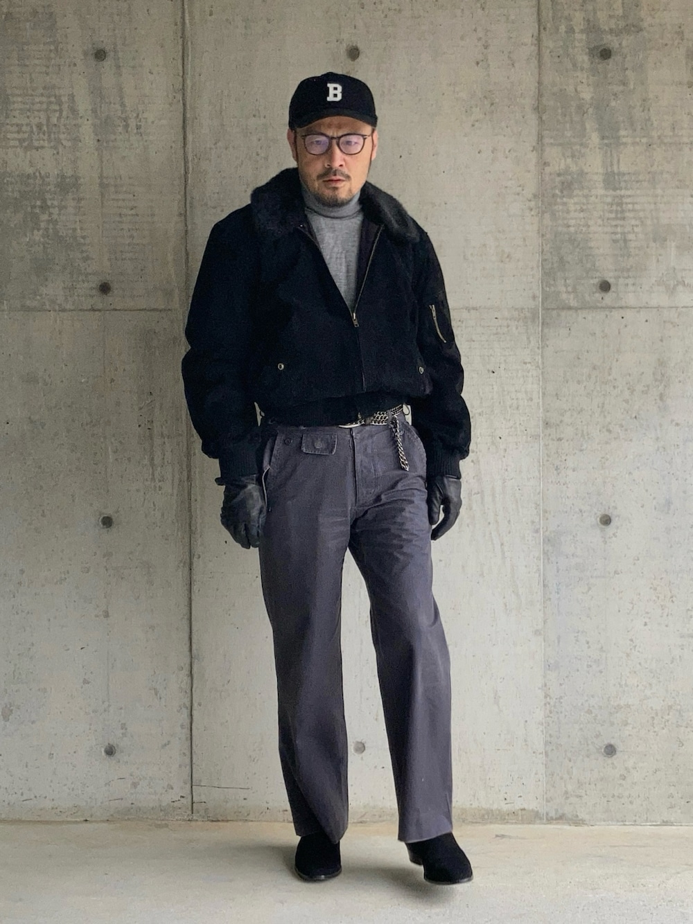 グレー系のニット/セーター、ブラック系のブルゾン、グレー系のスラックスを着用したメンズの冬コーディネートの1枚目の写真