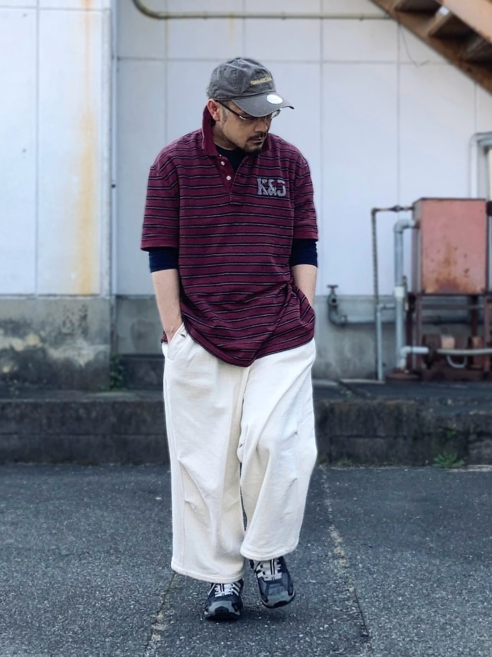 グレー系のスウェットパンツ、レッド系のポロシャツ、ブラック系のスニーカーを着用したメンズの春コーディネートの1枚目の写真