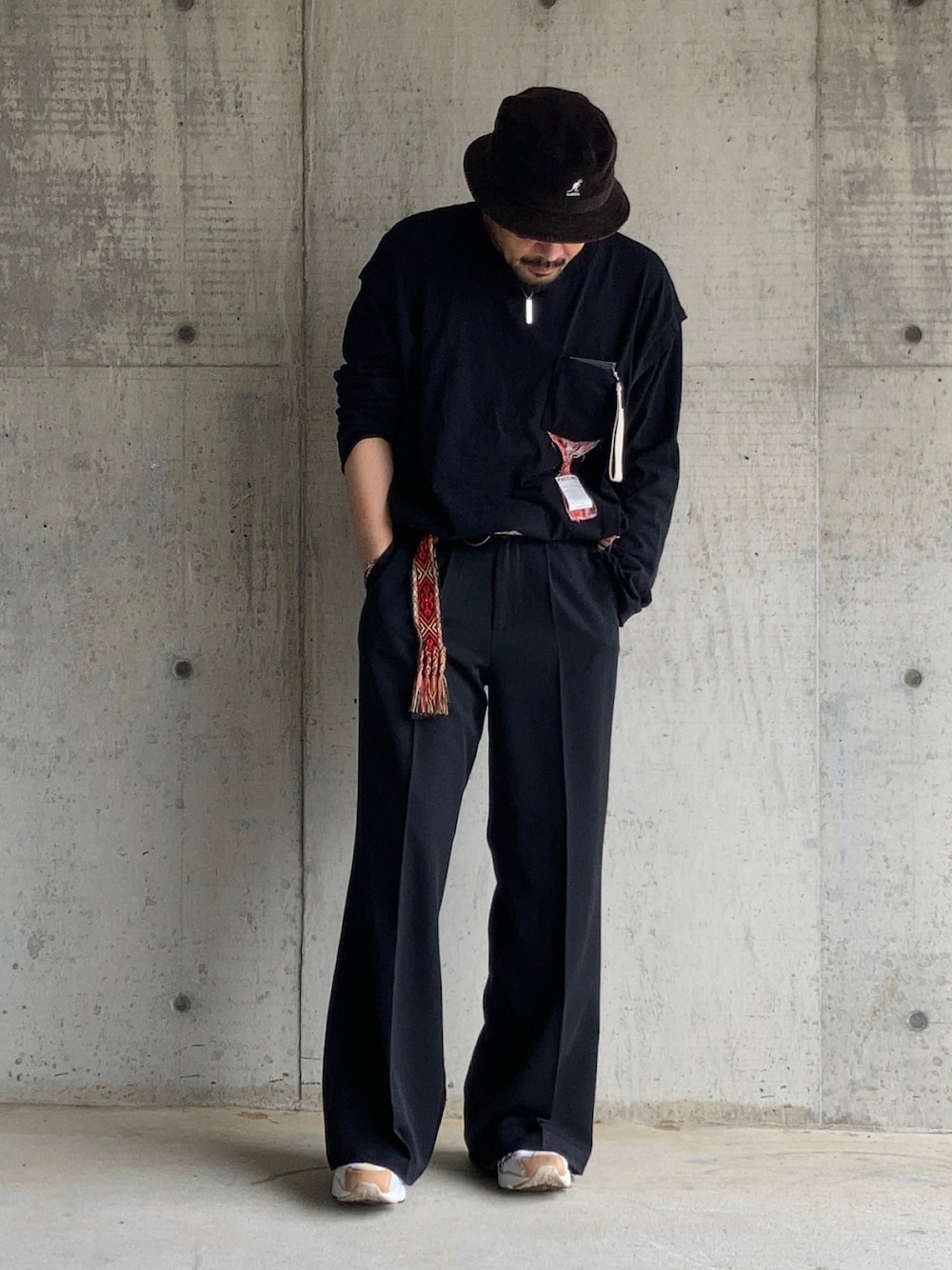 ブラック系のTシャツ/カットソー、ブラック系のスラックス、レッド系のスニーカーを着用したメンズの春コーディネートの1枚目の写真