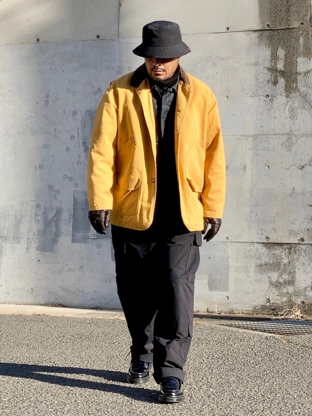 ブラック系のTシャツ/カットソー、ブルー系のデニムジャケット、イエロー系のカバーオールを着用したメンズの冬コーディネートの1枚目の写真