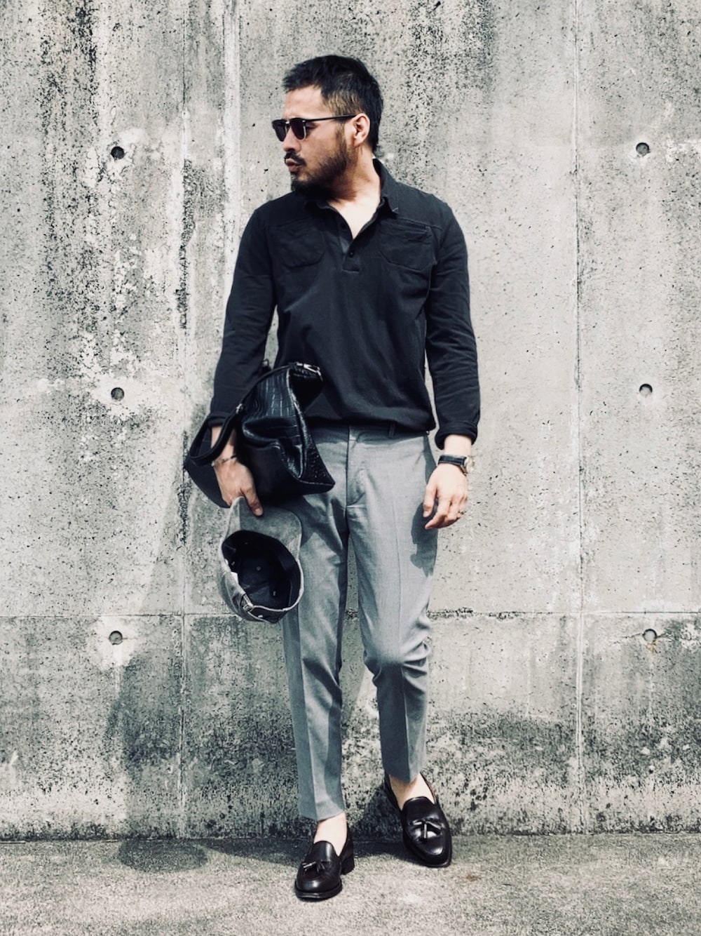 ブラック系のポロシャツ、グレー系のその他パンツ、ブラウン系のローファーを着用したメンズの春コーディネートの1枚目の写真