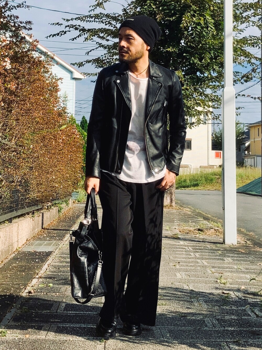 ピンク系のTシャツ/カットソー、ブラック系のライダースジャケット、ブラック系のスラックスを着用したメンズの秋コーディネートの1枚目の写真